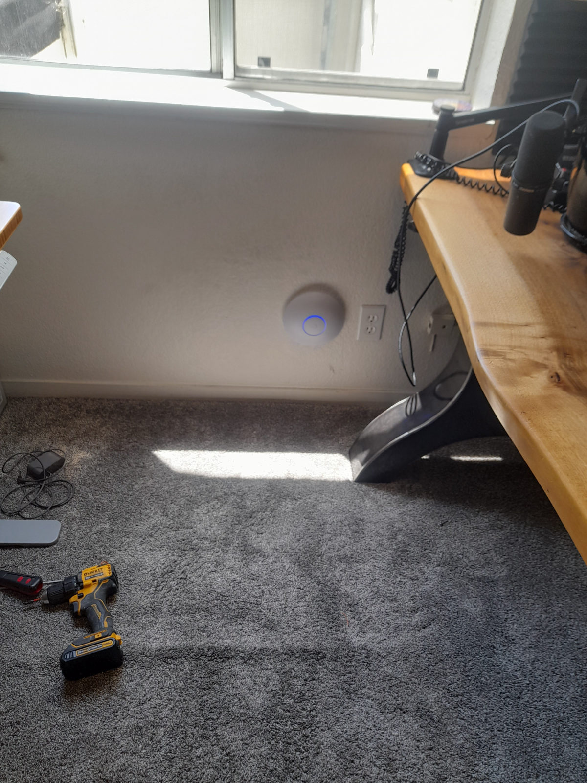 Wall-mounted UniFi access point beside a desk, status ring lit