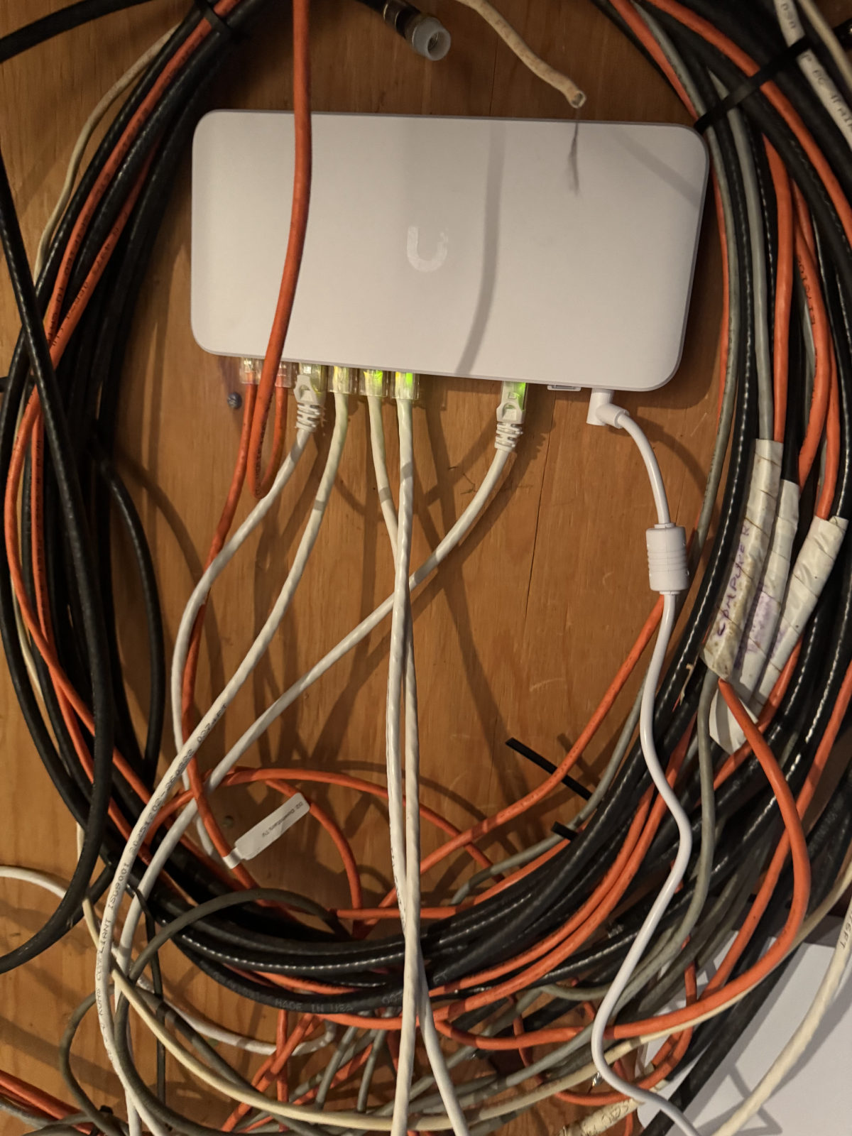 UniFi PoE device with several terminated Ethernet patch cables showing link lights and labels.b