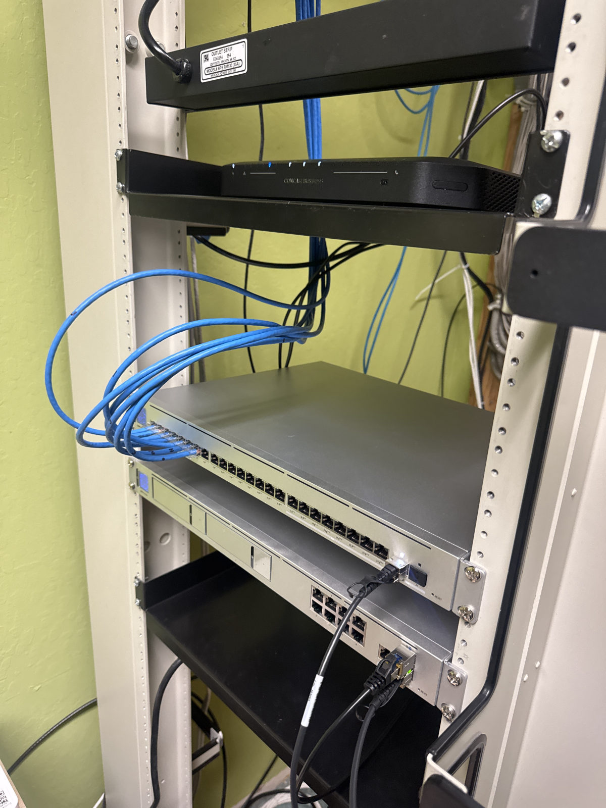 Wall rack with a 24-port PoE switch, gateway and bundled blue patch cables