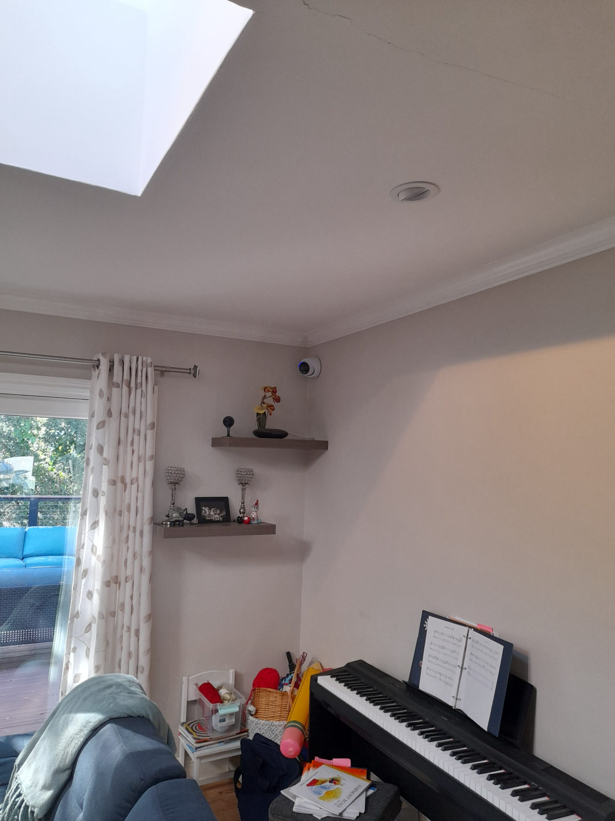 Indoor camera mounted high on a wall near the ceiling line of a living room