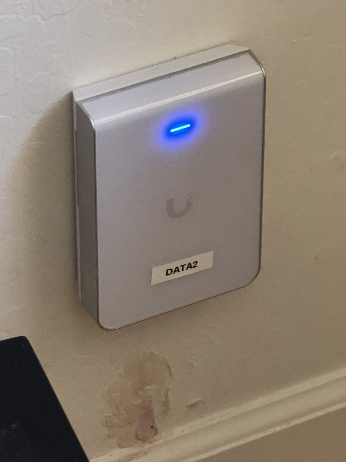 Wall-mounted UniFi access point labeled DATA2 with blue status light.